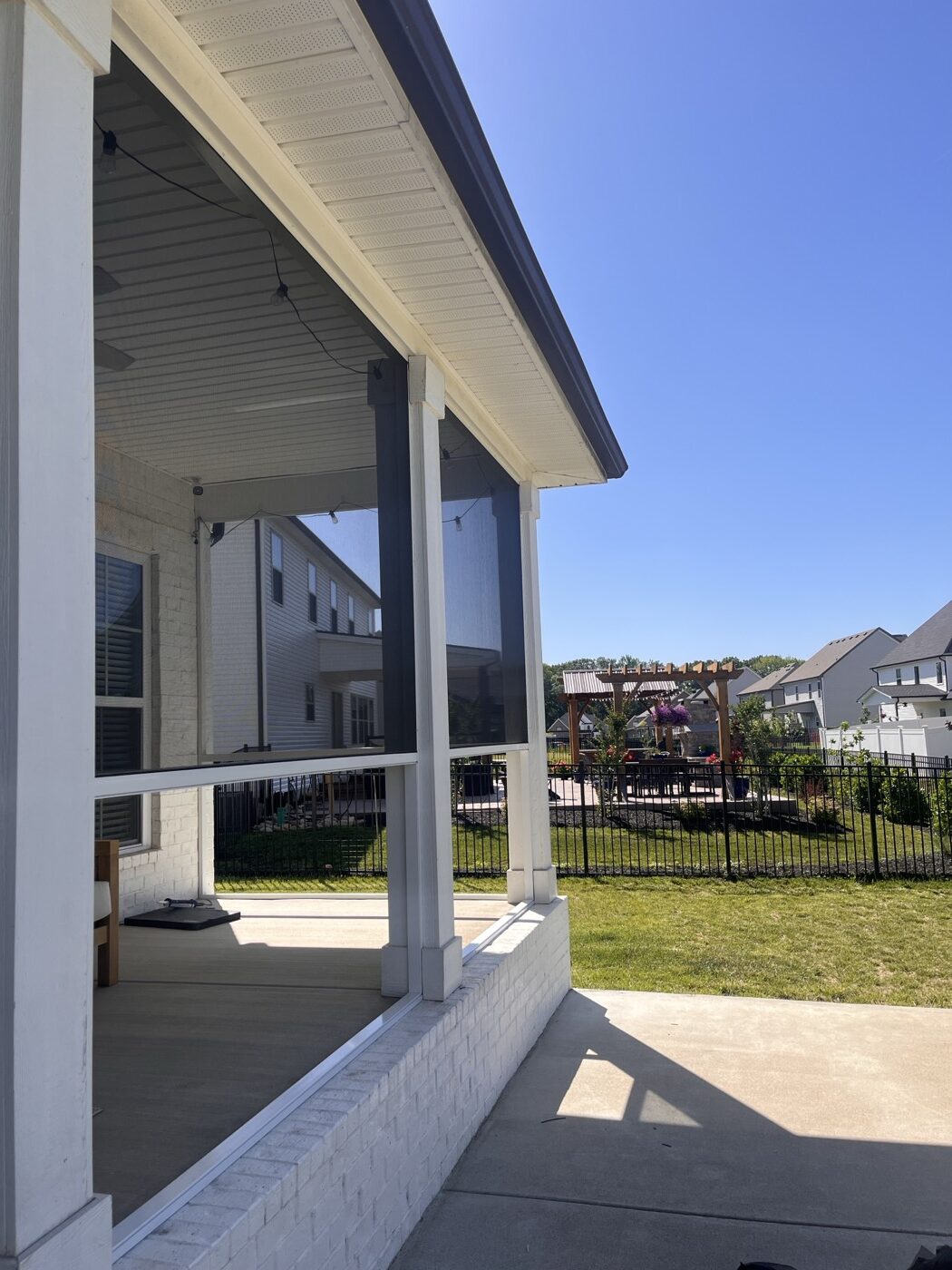 Covered screen room porch with white posts overlooking a landscaped backyard