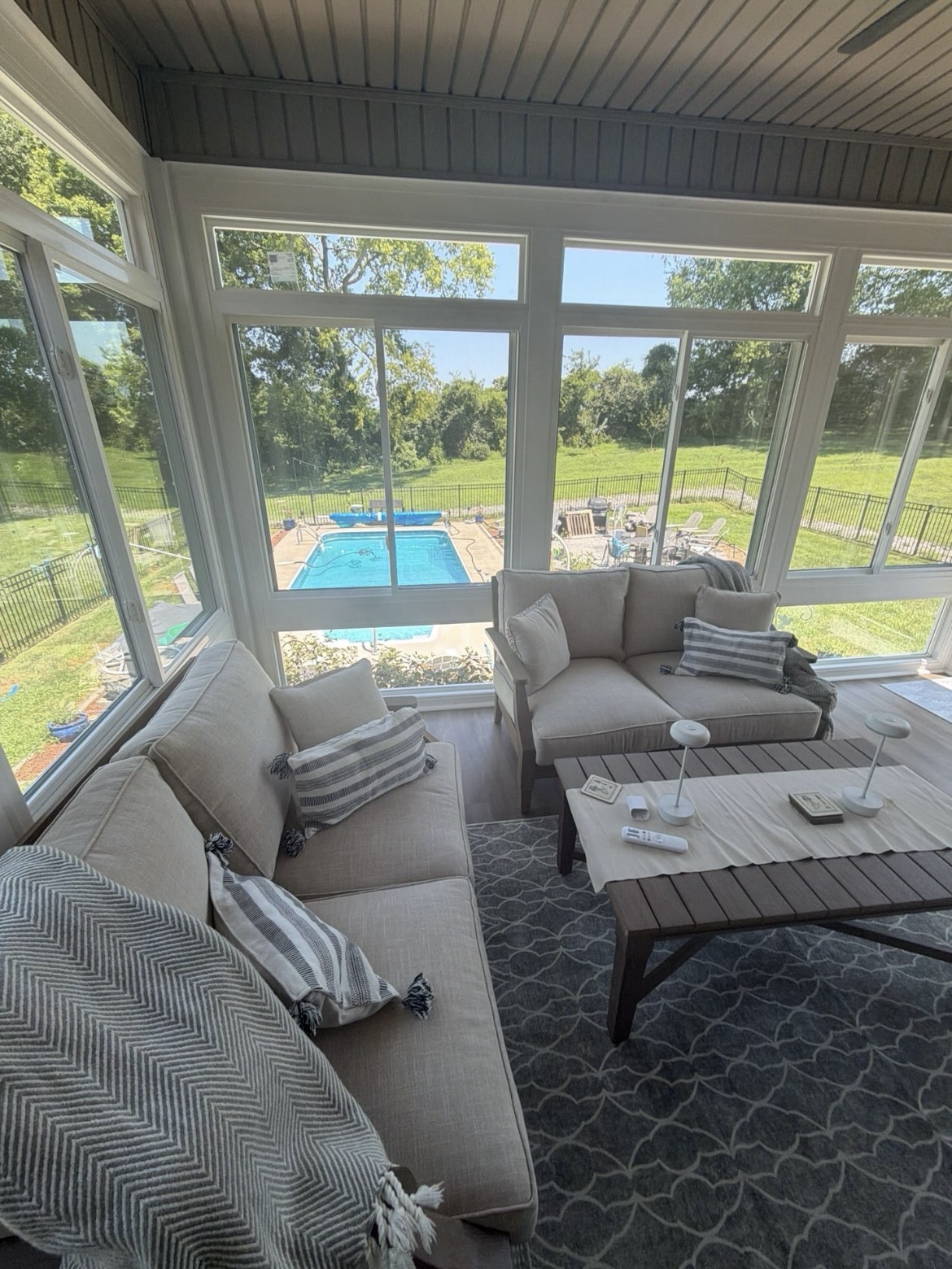 Four-season sunroom interior with large vinyl windows overlooking a backyard